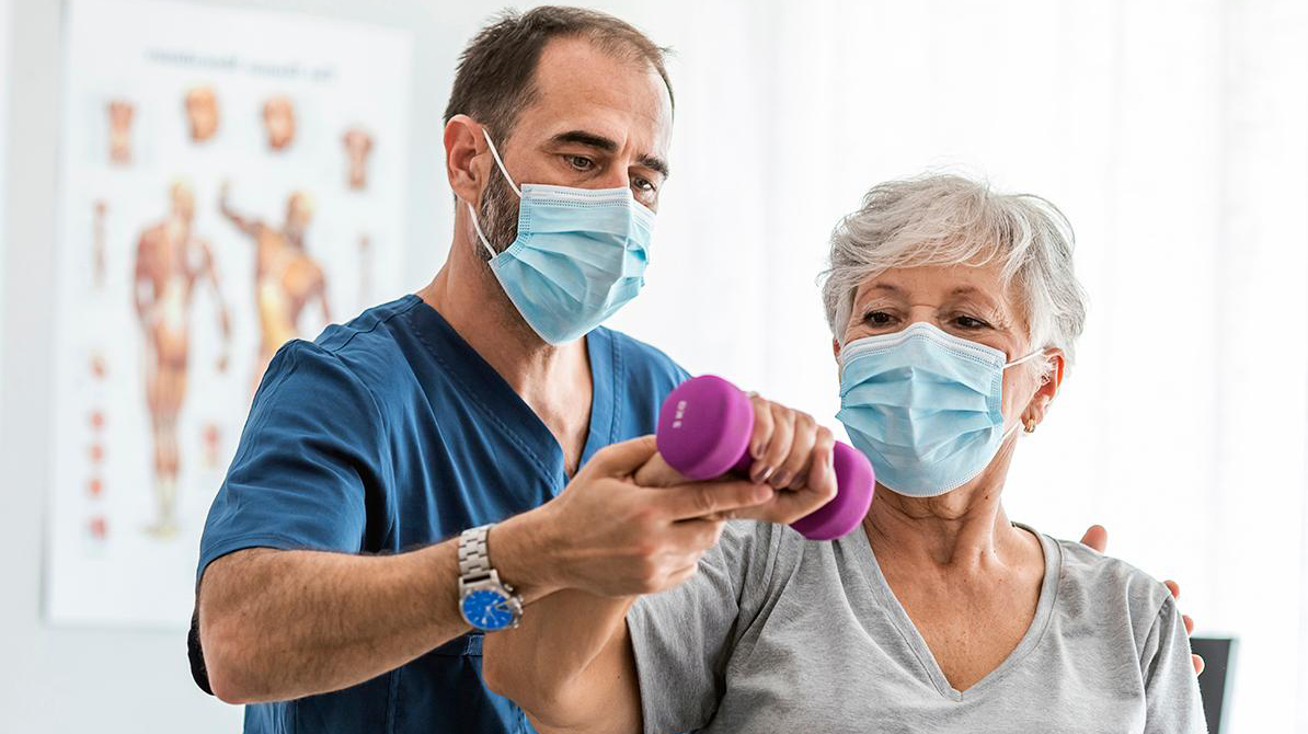 Fisioterapeuta atiende a persona mayor.